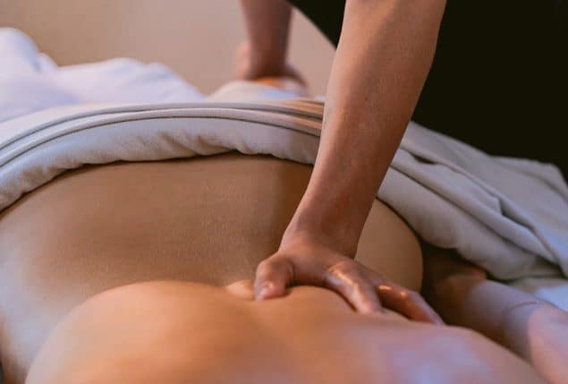 A close-up of a therapist performing a deep tissue massage on a client’s back. The therapist's hands apply firm pressure while the client lies under a soft towel, creating a calming and therapeutic spa experience. Title: Revitalizing Deep Tissue Massage for Muscle Relaxation